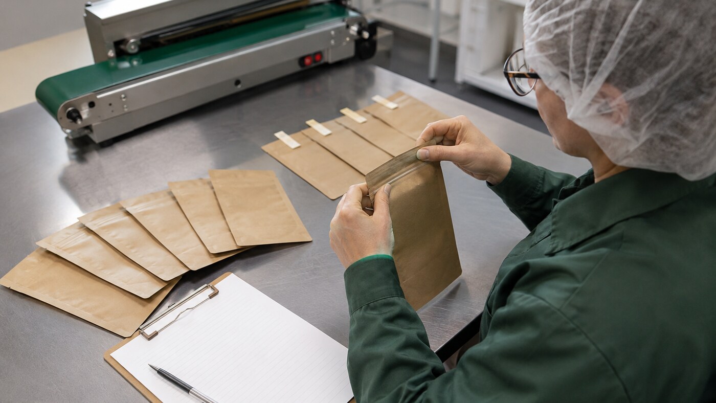 Packaging technician cycling pouch zippers during a documented production sample check
